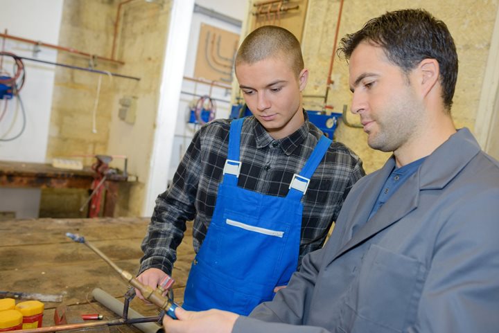 Man helping a teen learn on the job Man helping a teen learn on the job